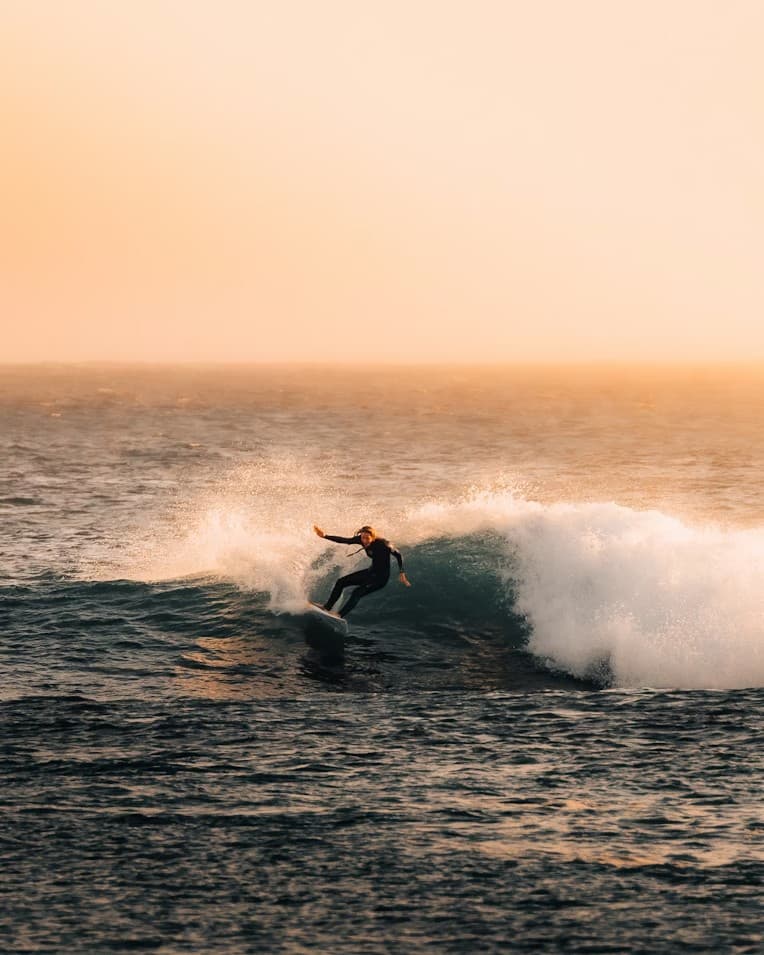 Surfer riding a wave at golden hour — Essaouira Surf Lessons