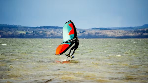 Wingfoileur en saut avec aile turquoise et orange à Essaouira — stockage matériel et test 20€